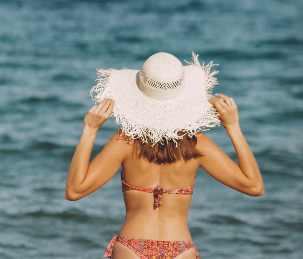 woman in a bikini with a sunhat heading into the water