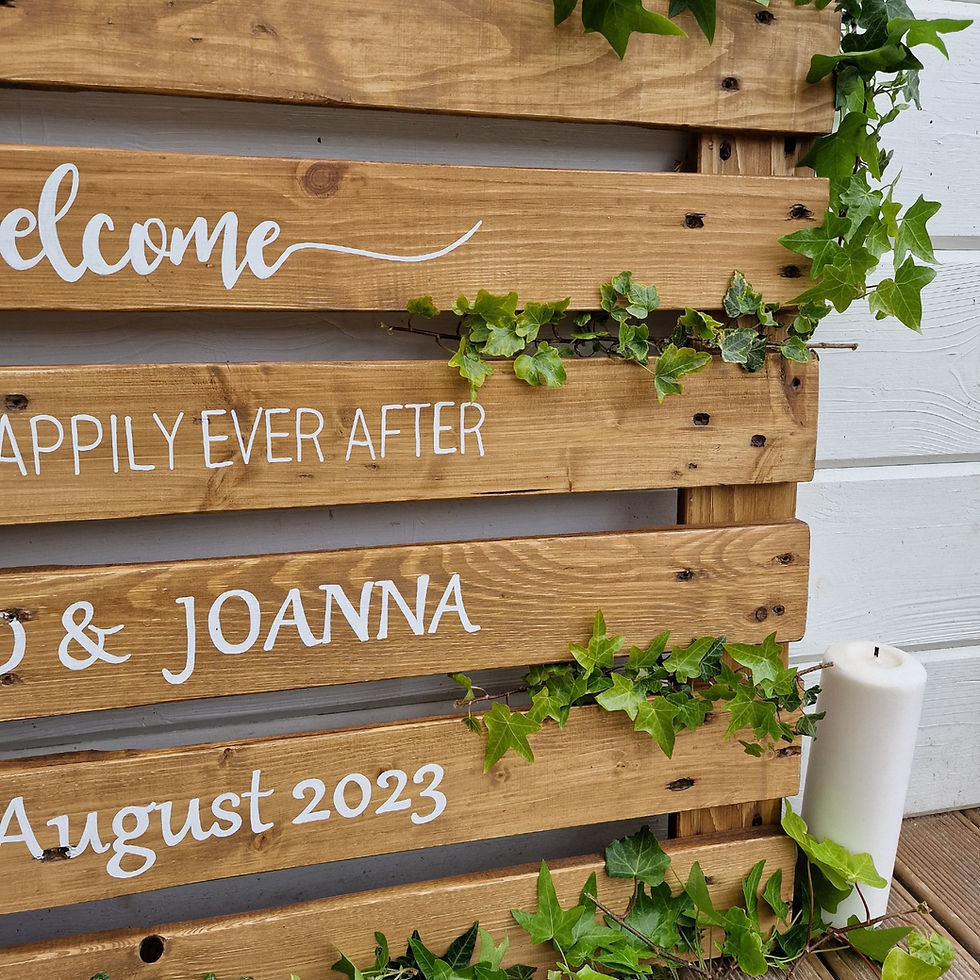Thumbnail: welcome wedding pallet sign with handwritten white font, paired with rustic pine cones and delicate ivy