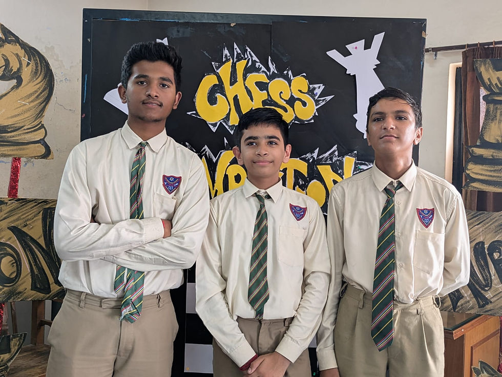Three schoolboys in uniform pose before a black-and-yellow CHESS TOURNAMENT backdrop, looking calm and proud.