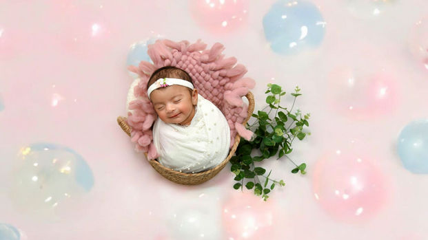 Sleeping newborn baby girl in basket, pink balloons Shri Krishna Photography