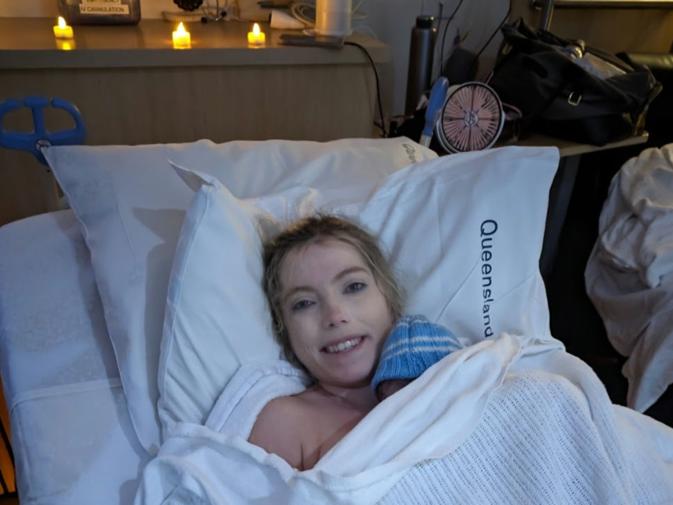 Smiling woman just given birth having skin to skin with baby
