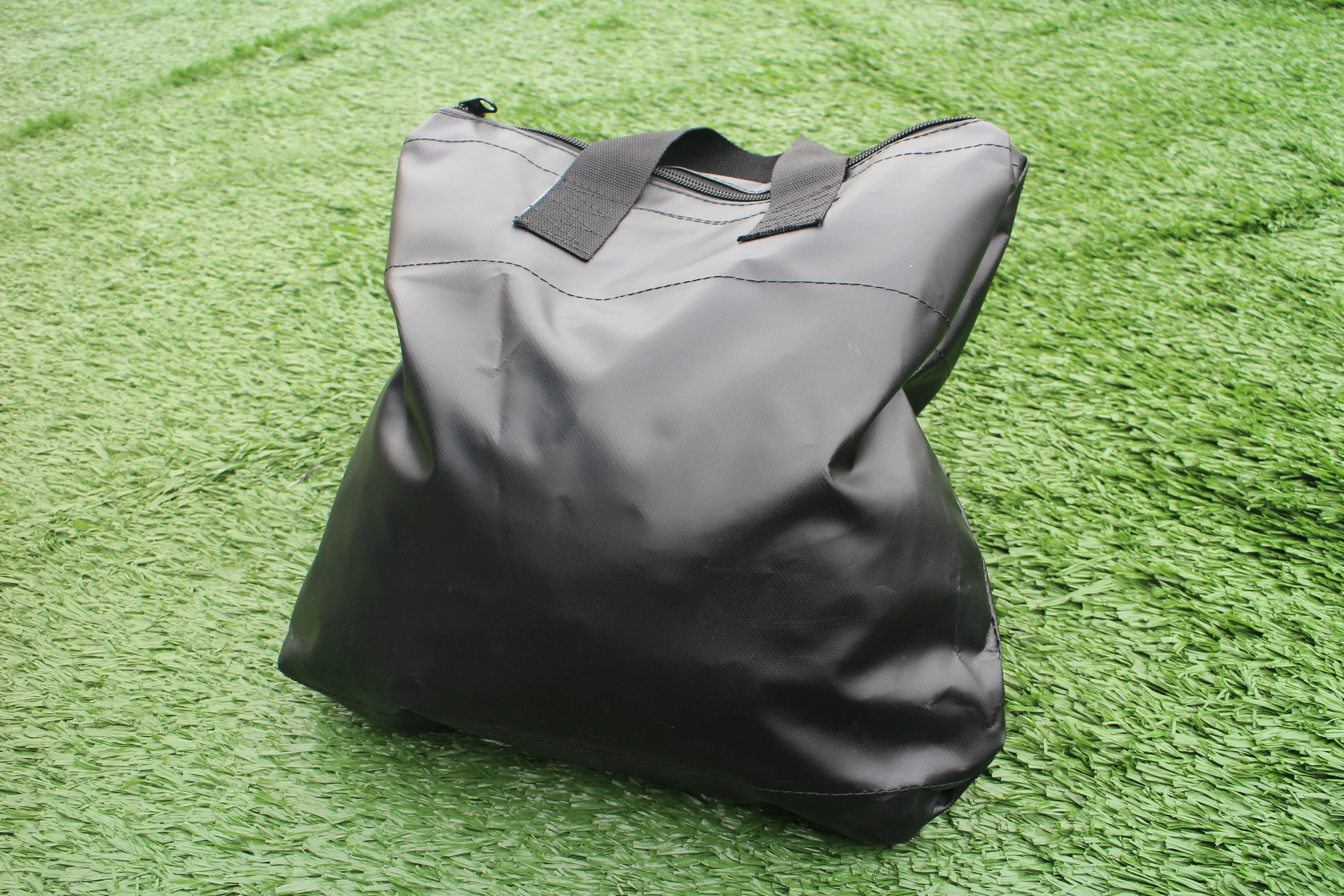 Upright view of black canopy sandbag positioned on green turf