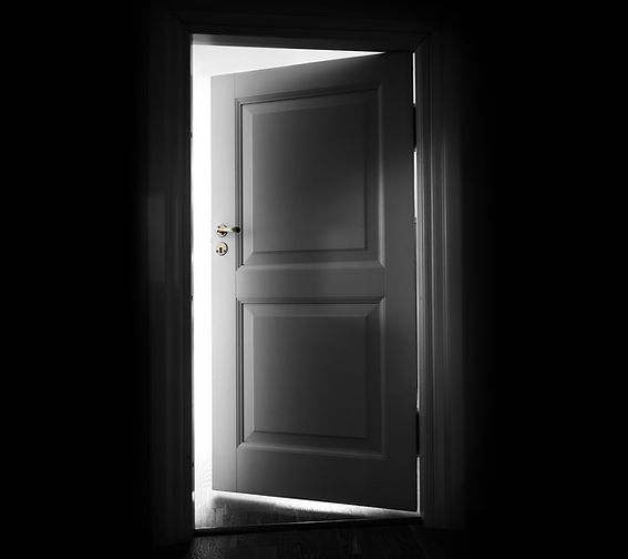 Opening white door in a dark room with light outside.jpg