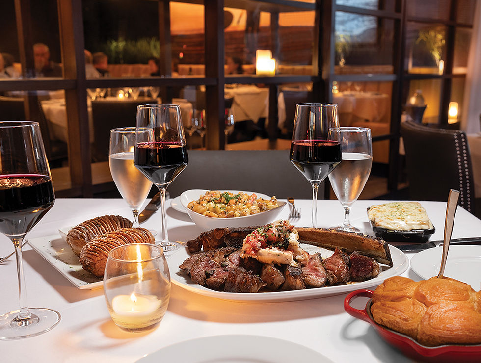 A table set with steak, lobster, wine in glasses