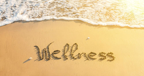 A beach setting showing Wellness written in sand