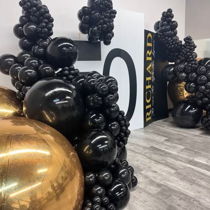 Black and gold balloon decoration featuring "50" numbers and "RICHARD" sign.