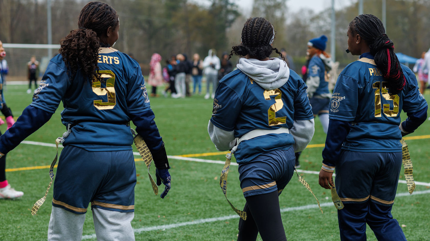 Three young athletes wearing jerseys with numbers and 