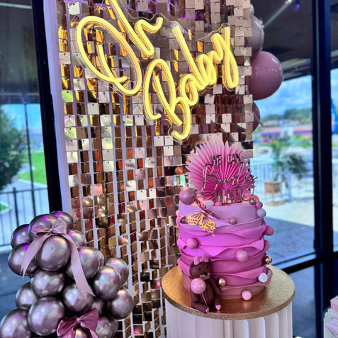 Pink ombré cake, "Oh Baby" neon sign, gold sequin backdrop.