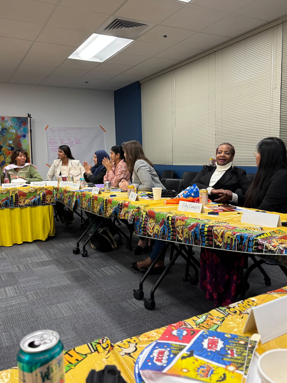Attendees gathered around a table with colorful tablecloths at a community event.