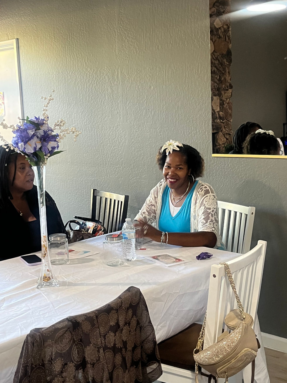 Two smiling women seated at white table with floral centerpiece.