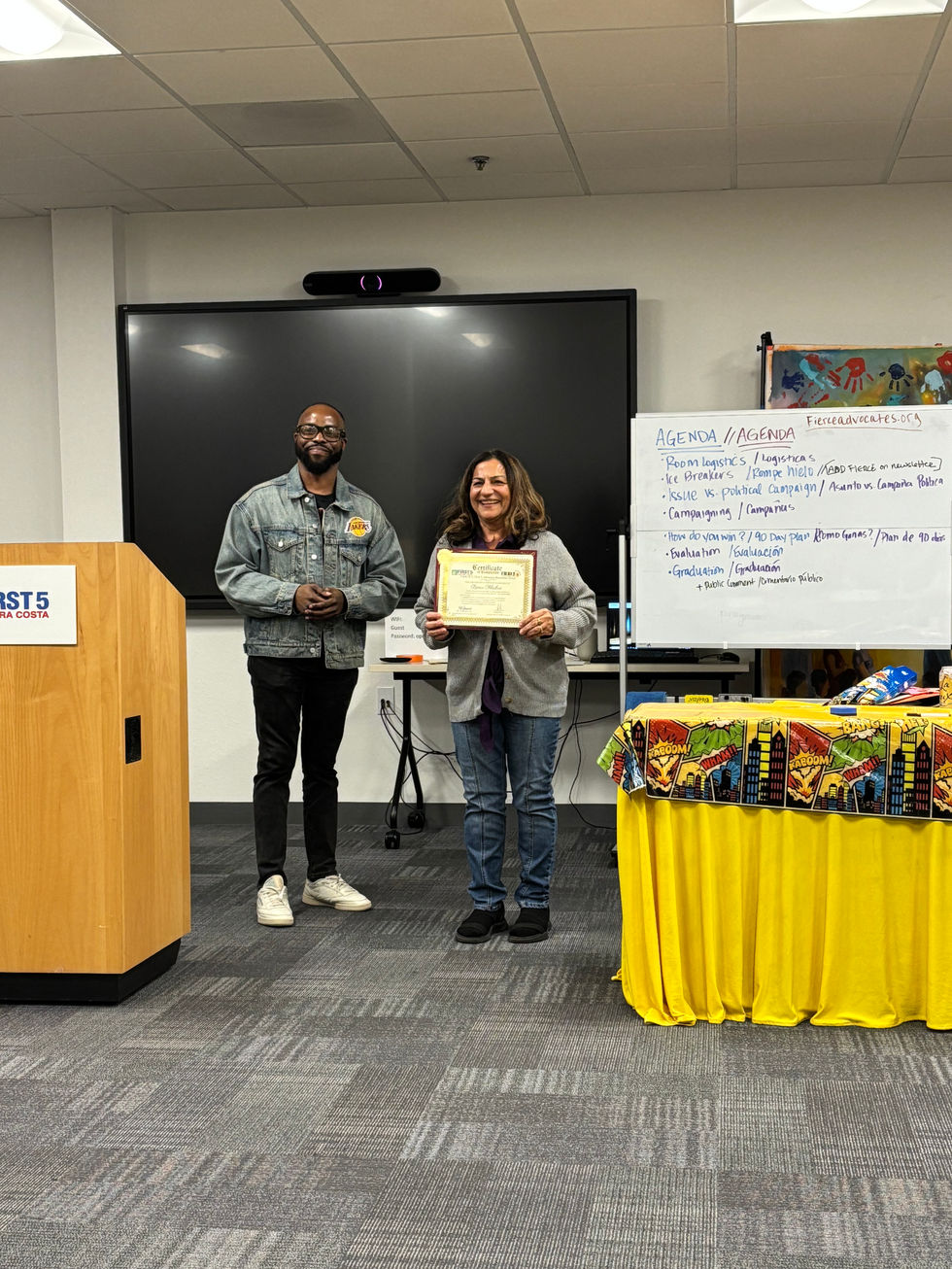 Two people, woman holding a certificate, standing in presentation room.