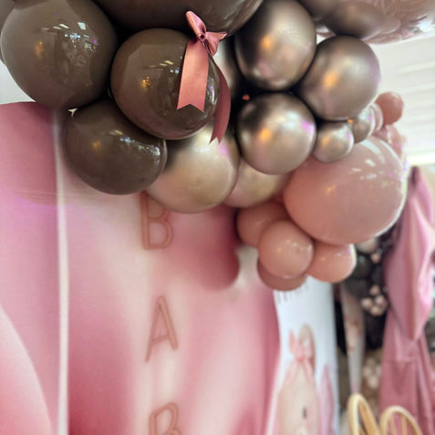 Pink, brown, metallic balloon arch with "BABY" text backdrop.