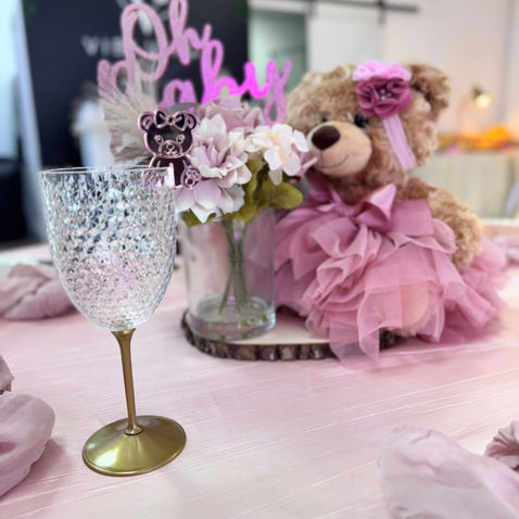 Clear wine glass, teddy bear, "Oh baby" sign, pink baby shower decor.