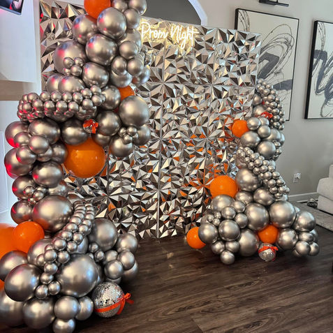 Silver and orange balloon party arch decor with 'Twenty One' sign.