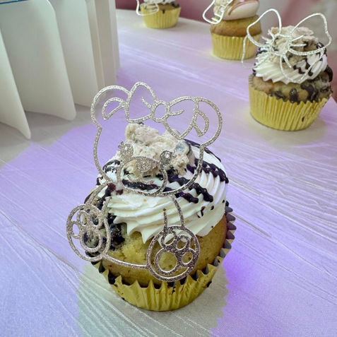 Decorated cupcake with white frosting, chocolate drizzle, and gold glitter topper.