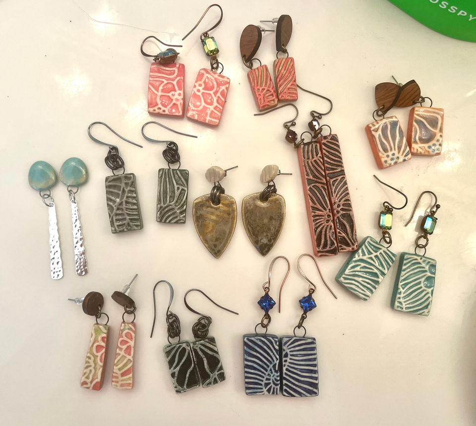 Collection of colorful handmade earrings displayed on a white surface closeup view.