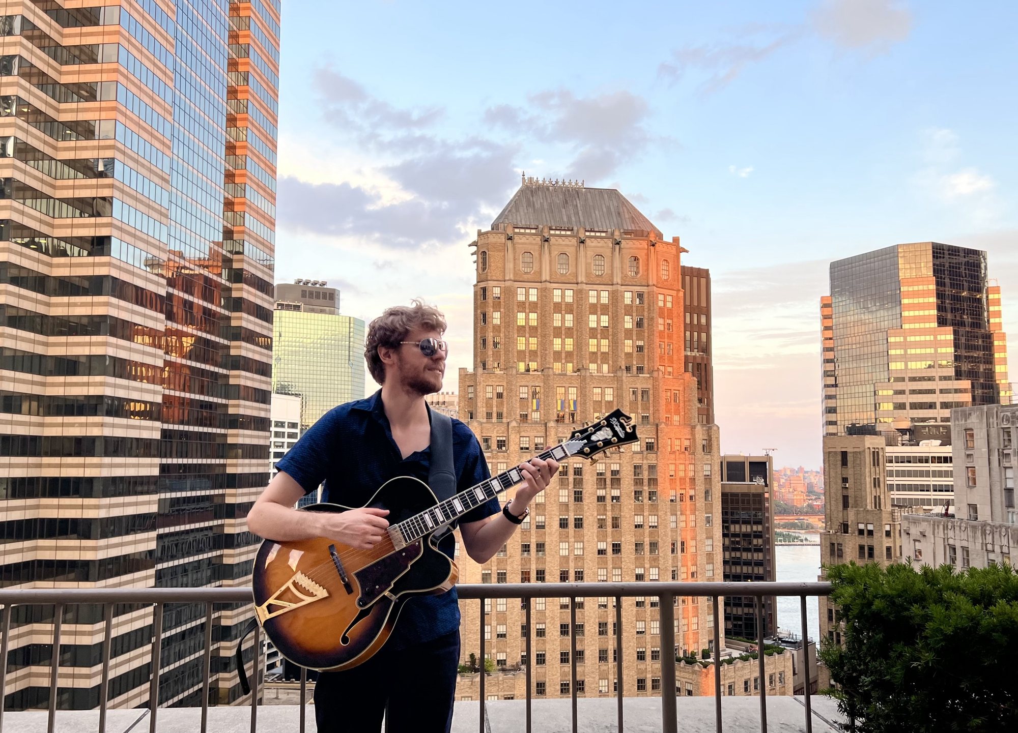 Hans Luchs playing his archtop guitar on a Manhattan rooftop at sunset