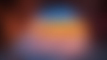 Ocean shoreline at sunset seen from inside a rock cave, with calm waves and warm horizon light.