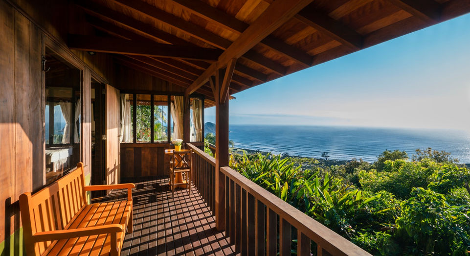 Ampla varanda fechada de madeira de lei do Chalé Master 2 com bela vista para a Praia do Rosa no amanhecer