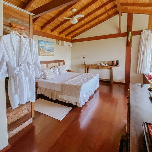 Interior do quarto de casal do aconchegante Chalé Master 2, com muita madeira e decoração aconchegante e confortável, roupões de algodão macios