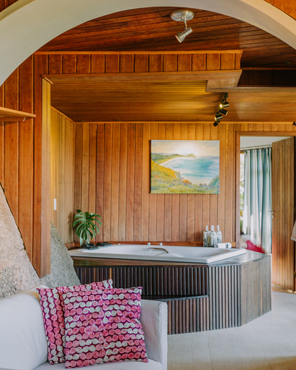 Interior da Suíte com Rochas Naturais, Banheira de Hidromassagem e Muita Madeira de lei nas paredes e teto, chão de porcelanato claro