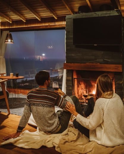 Casal descansando na frente da Lareira tomando um vinho tinto e curtindo a vista da Praia do Rosa com Lua cheia