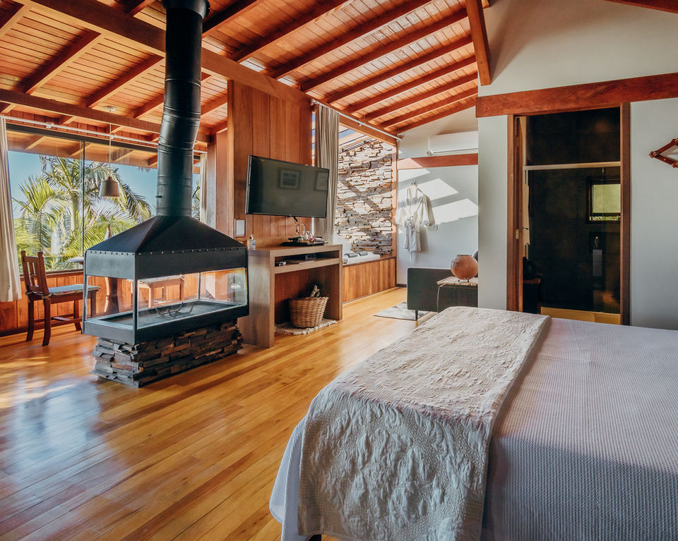 Vista Geral do Aconchegante e Amplo Interior do Chalé Master Plus 1 com Cama Queen, Lareira Central e SmartTV e luz natural do amanhecer