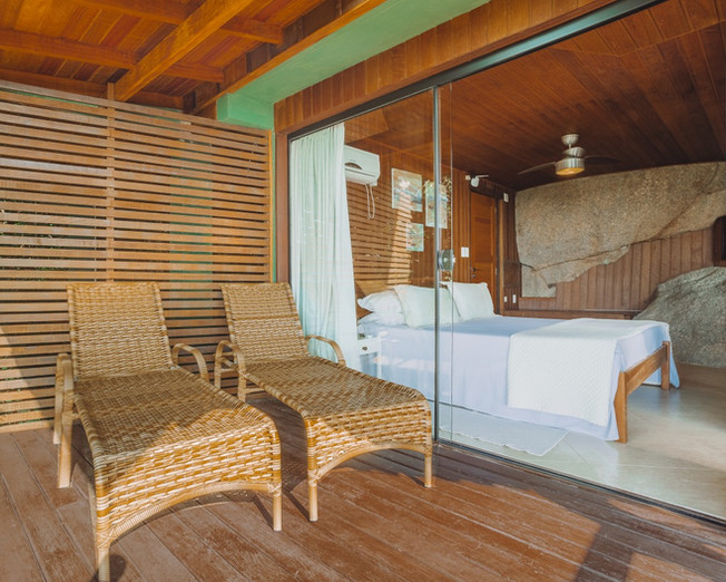 Espreguiçadeiras na Varanda Coberta e Interior do Quarto com Cama Queen Size e rochas do terreno