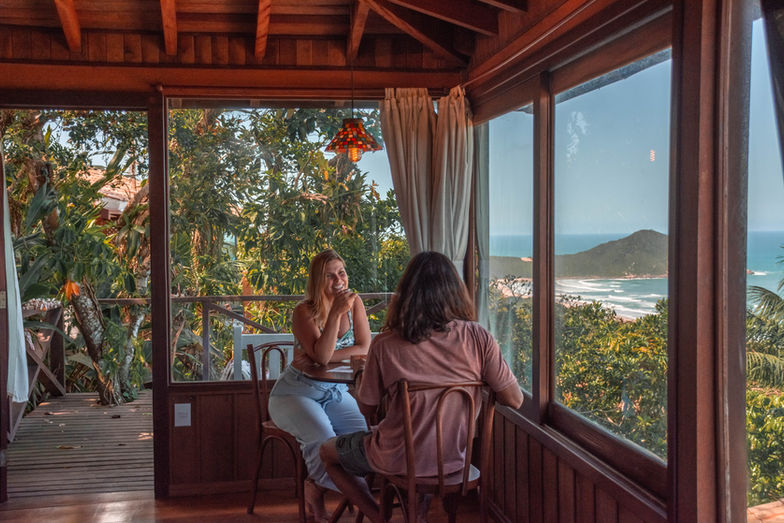 Casal sentado apreciando a tranquilidade e a belíssima Vista da Praia do Rosa e a natureza do entorno do chalé