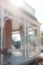 Intricate details of off-white railings and columns on a Victorian home attached to a porch.