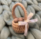 A crochet Easter basket, with a ribbon, filled with chocolate eggs.