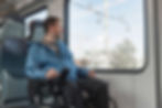 man in wheelchair looking out the window of a bus