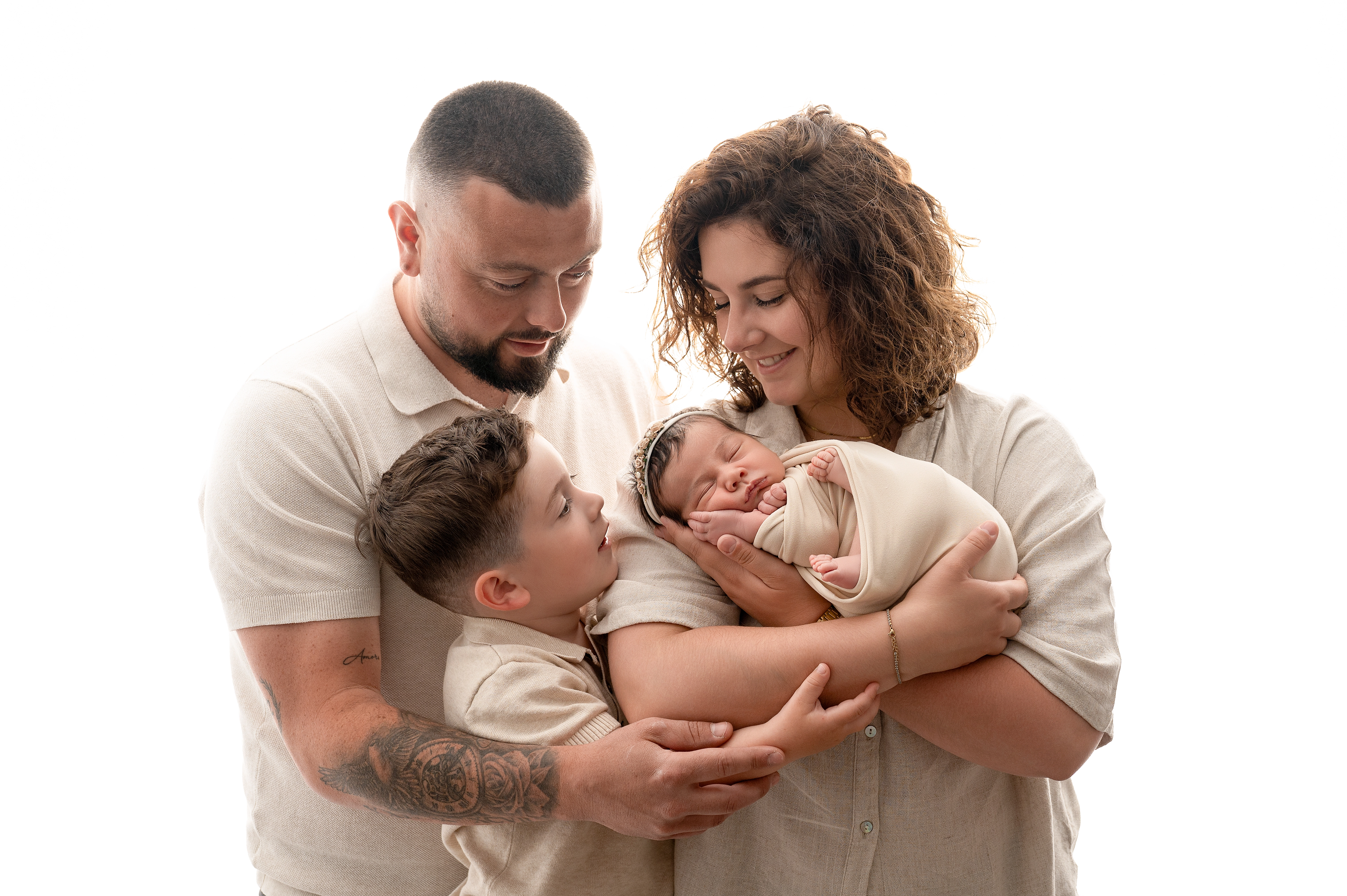 arents et grand frère entourant avec tendresse un nouveau-né lors d'une séance photo naissance en studio à Dreux.
