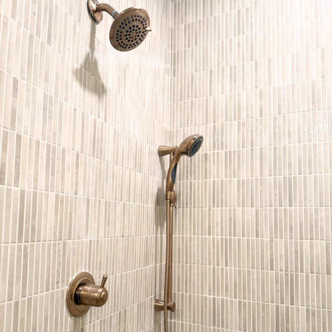 A shower head with a wand and vertical tile.