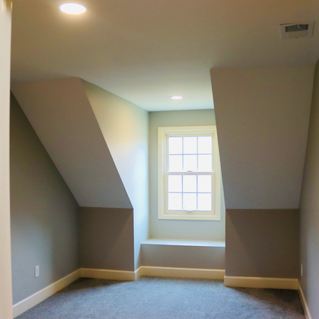A bedroom with dormers on each side of a window.