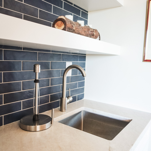 A kitchenette with blue subway tile behind the sink
