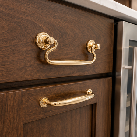 Dark wood custom cabinetry with polished brass drawer pulls and luxury built-in storage details in a high-end kitchen.