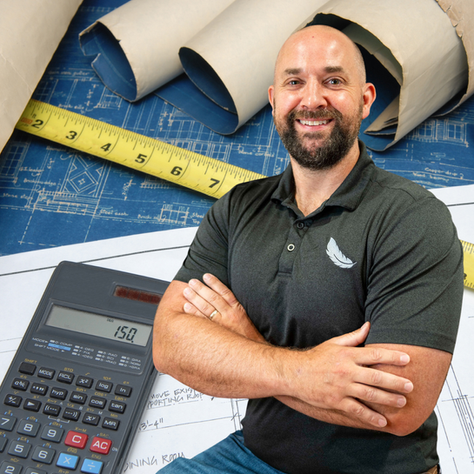 A handsome man is standing in front of a construction estimate with his arms crossed.