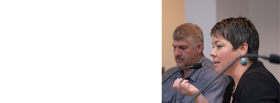 Photo of Betsy speaking into a mic, next to a man.