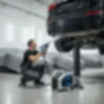 Mantenimiento y limpieza de chasis de vehículos en elevador automotriz. Un técnico inspecciona y prepara la zona del neumático y el bajo del coche para detailing o servicio profesional con equipo especializado.