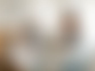 Una mujer latina de 38 años descansa cómodamente en una habitación moderna en Quito tras una biopsia de corteza renal, mientras una acompañante le acomoda la almohada en una cama con decoración celeste y naranja.
