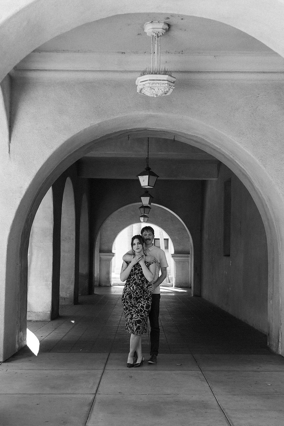 Owner of Devine Styles and her fiance. Standing under a concrete building archway
