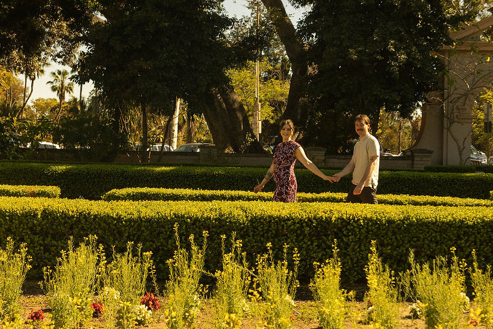Owner of Devine Styles and her fiance, holding hands, walking through a flower garden