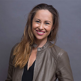 Smiling woman wearing taupe leather jacket with long blondish brown hair