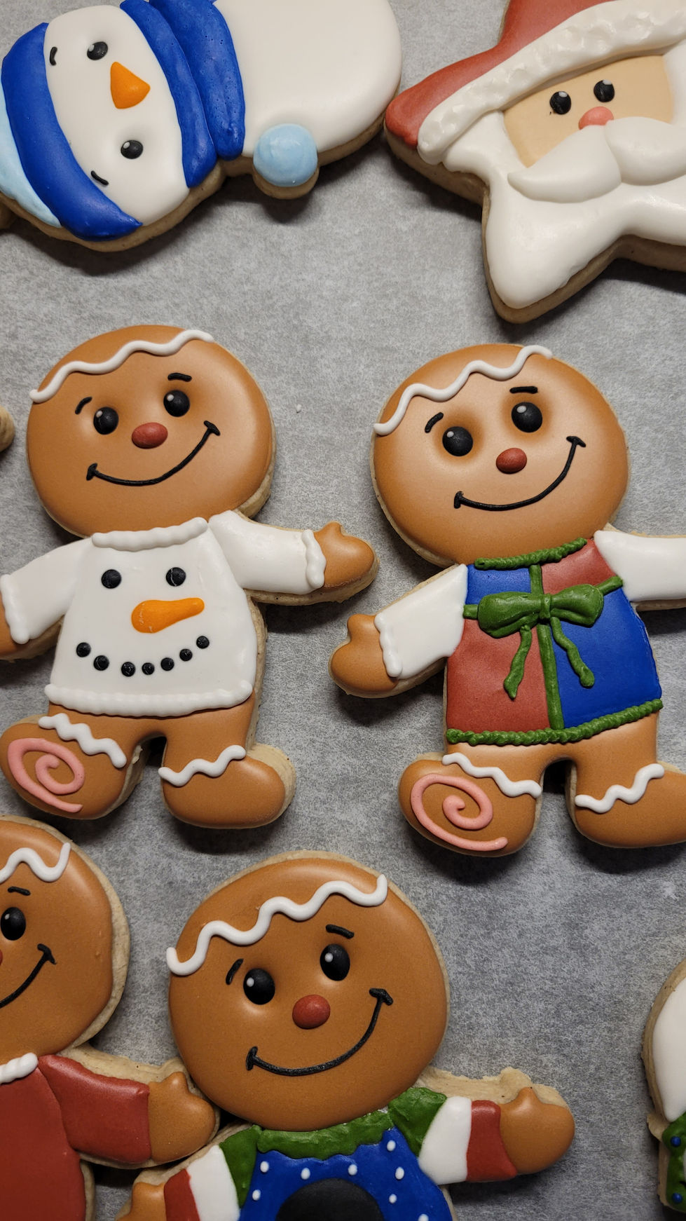 Two gingerbread man cookies smiling with colorful tops, baked goods.