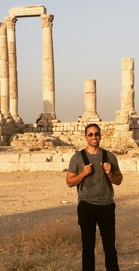 Background image is of Thomas smiling with Roman columns in background, wearing gray tshirt and jean
