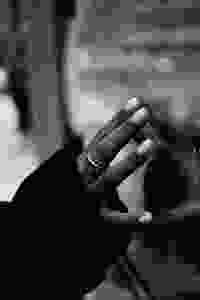 Close up black and white photo of a hand reaching out to touch a window