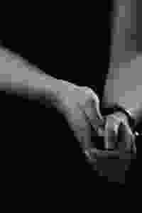 Close up black and white photo of hands almost clasped, with a bracelet on their left wrist