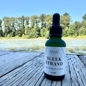 ARAU Sleek Strand Hair Essence bottle photographed beside the water in Langley, British Columbia.
