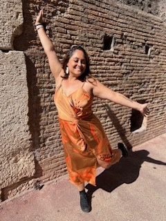 a woman posing in front of a wall in the Colosseum